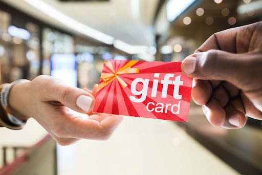 Two hands exchanging a gift card